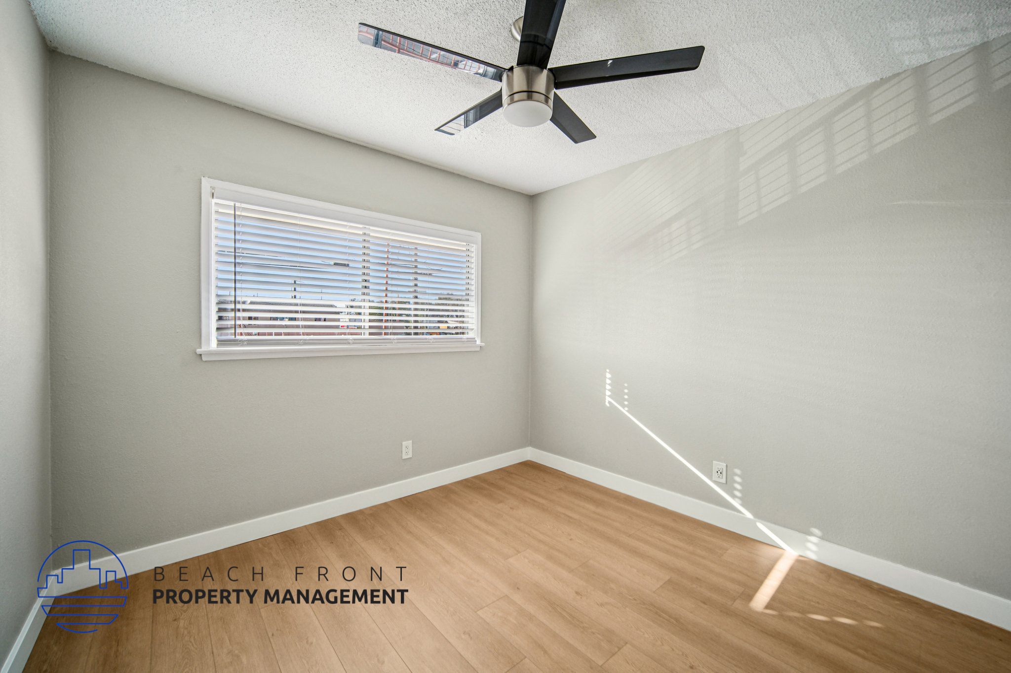 A room with a ceiling fan and a window with blinds.
